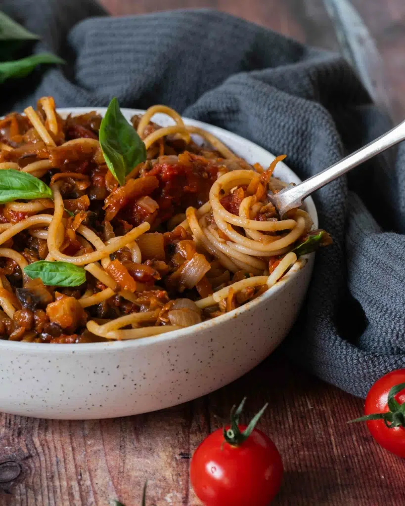 A bowl of vegan bolognese with a forkful of spaghetti twirled in the bowl.