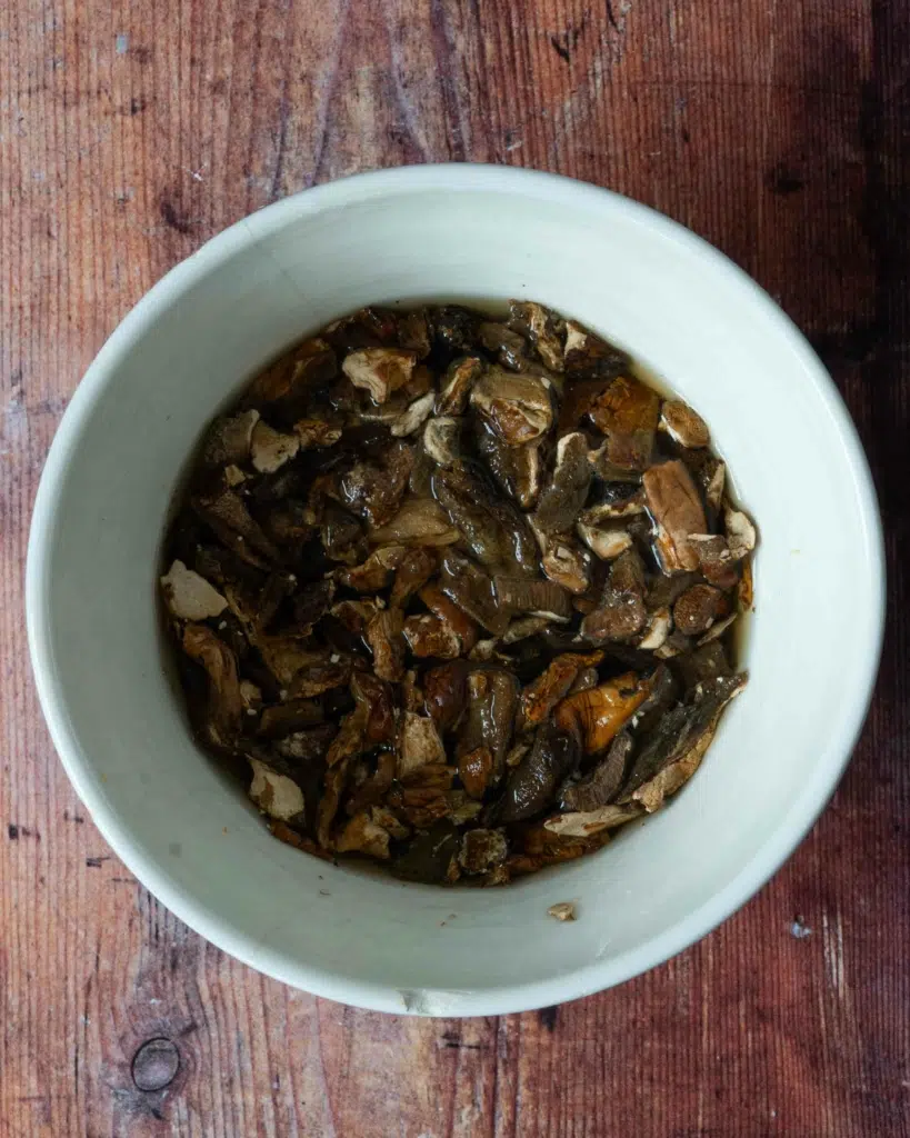 Dried wild mushrooms rehydrating in a bowl of hot water