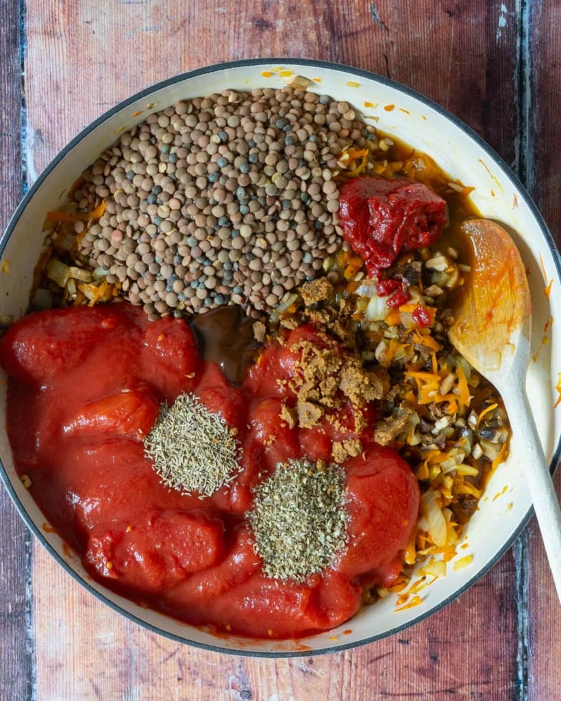 The ingredients for vegan bolognese in a large frying pan, about to be stirred