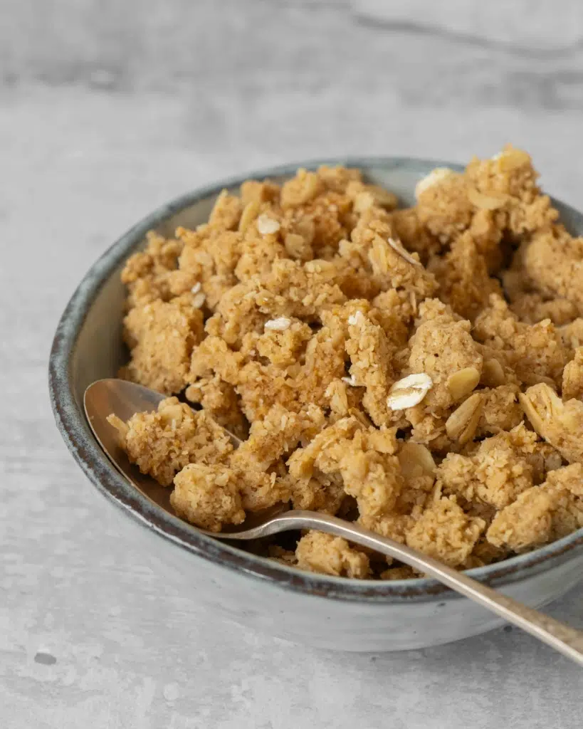 An up-close shot of a bowl of oatmeal crumble topping, with lots of little crunchy clusters of topping.