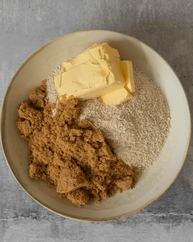 Vegan butter, oat flour and brown sugar in a bowl ready to be mixed together to make crumble topping.