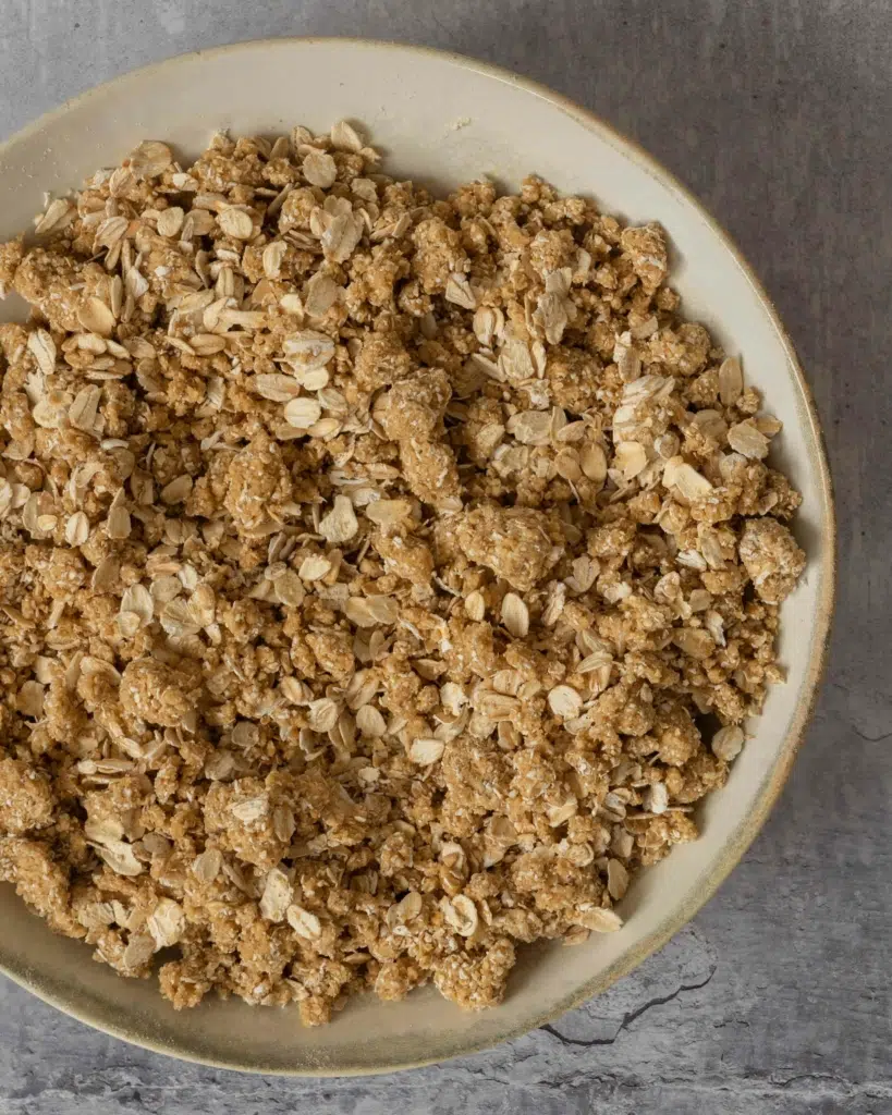 The final step of how to make oatmeal crumble topping. This process shot shows the crumble mixture having been mixed together with some whole oats.