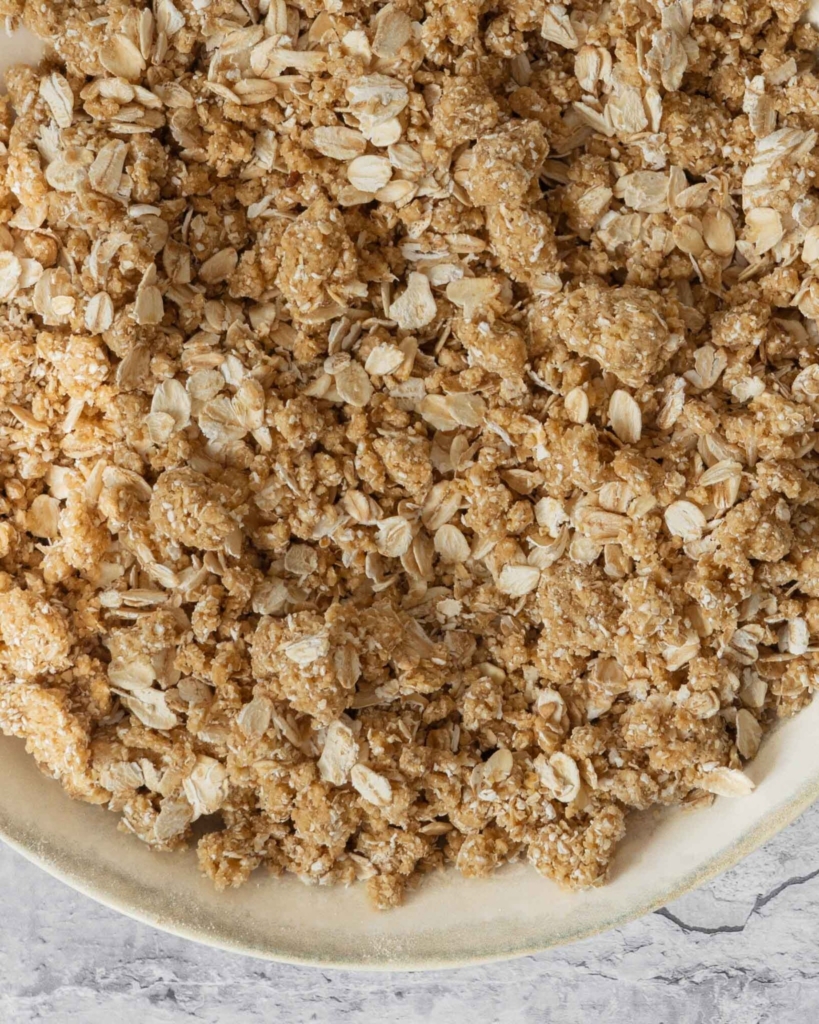 A close up photograph of freshly mixed oatmeal crumble topping, before it has been baked.