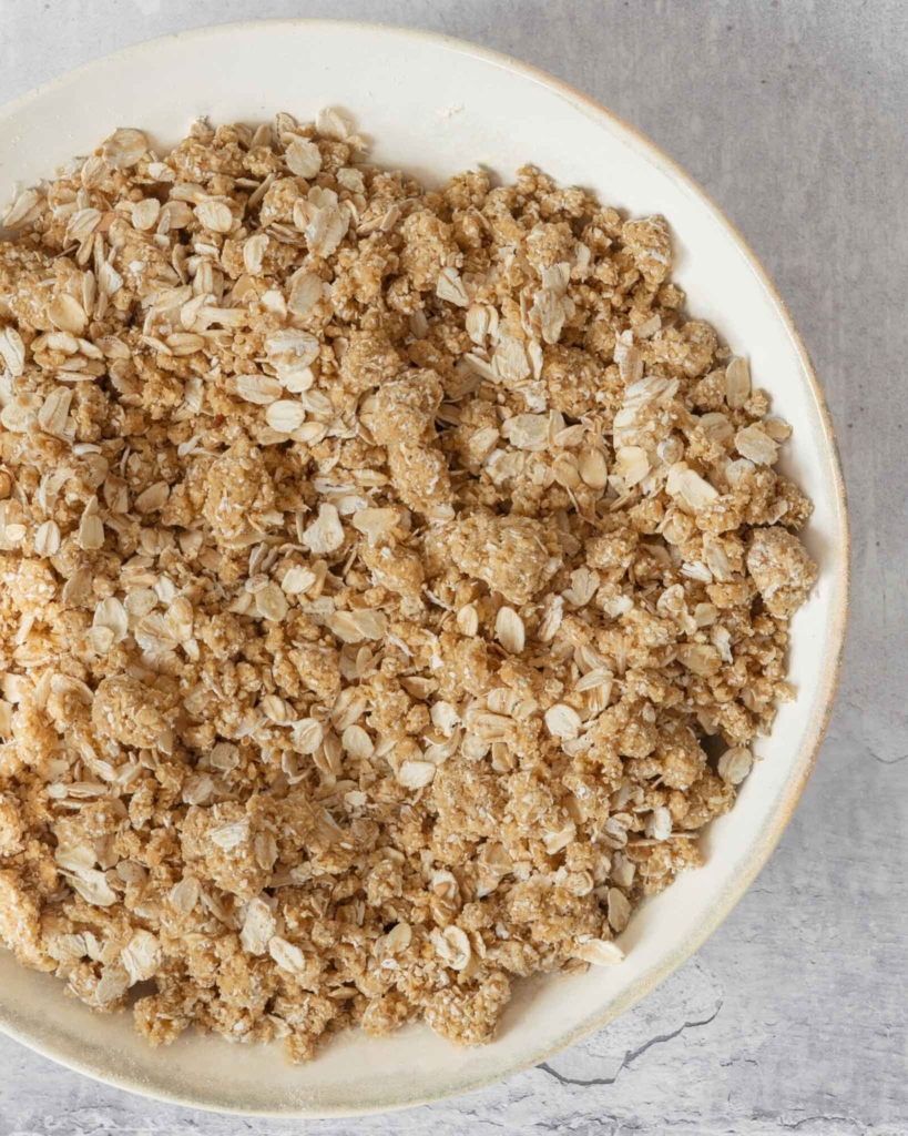 A close up photograph of freshly mixed oatmeal crumble topping, before it has been baked.