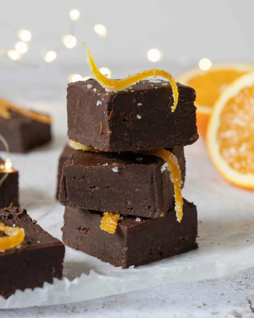 A stack of three squares of chocolate orange 5 ingredient fudge, topped with homemade candied orange peel