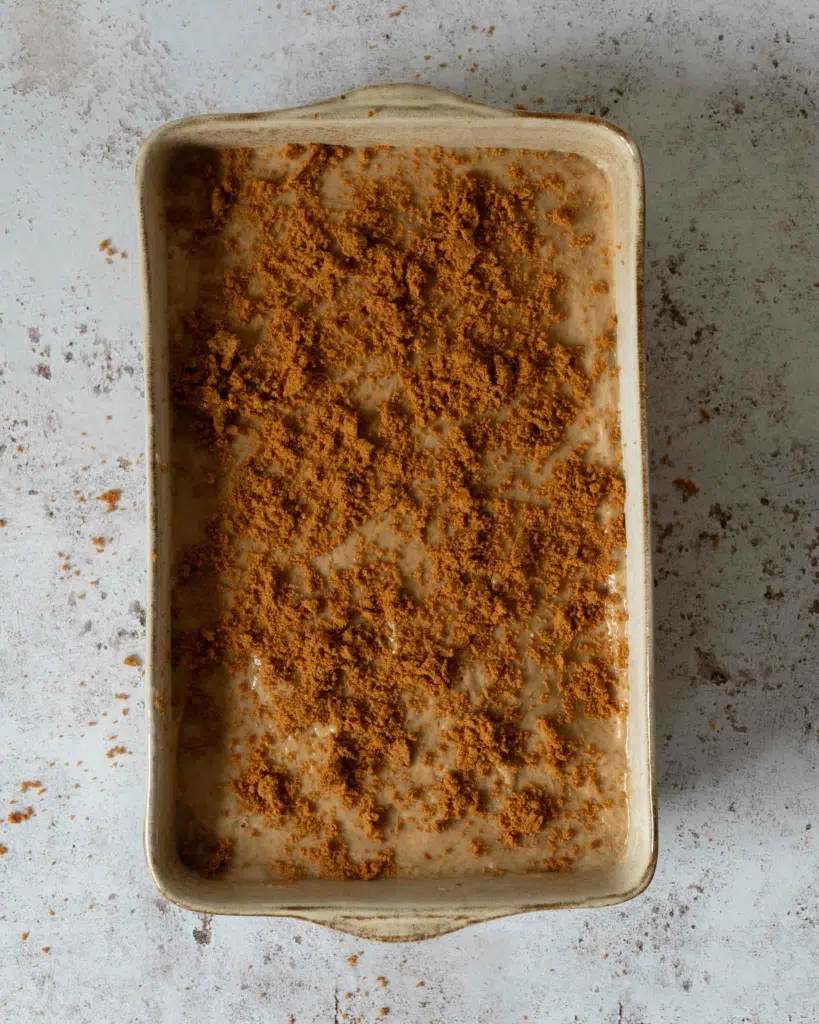 A finished vegan Biscoff tiramisu in a rectangular dish, topped with crumbled biscuit crumbs