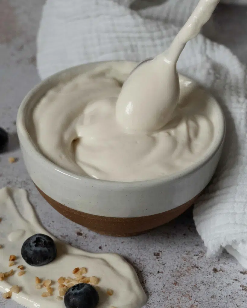 A spoonful of vegan mascarpone being lifted out of a bowl