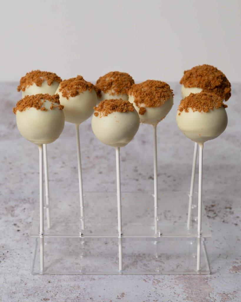 Pretty white chocolate Biscoff cake pops stood in a cake pop stand