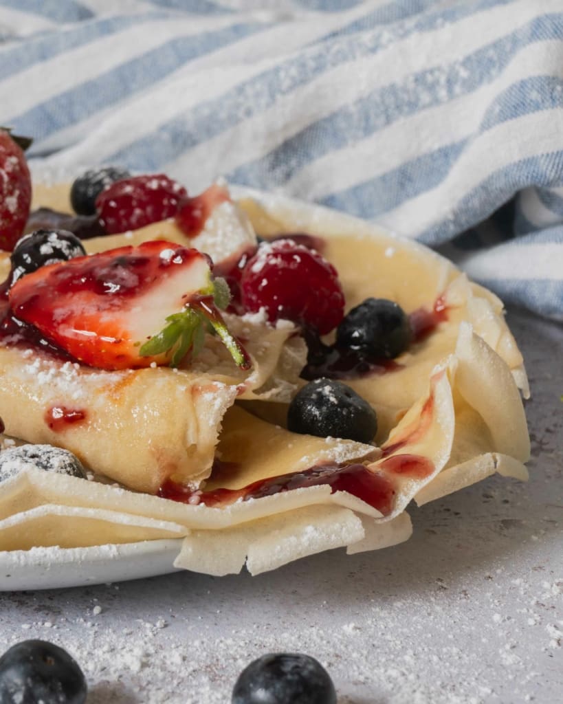 A side on photograph of a plate of vegan crepes, showing the crispy edges