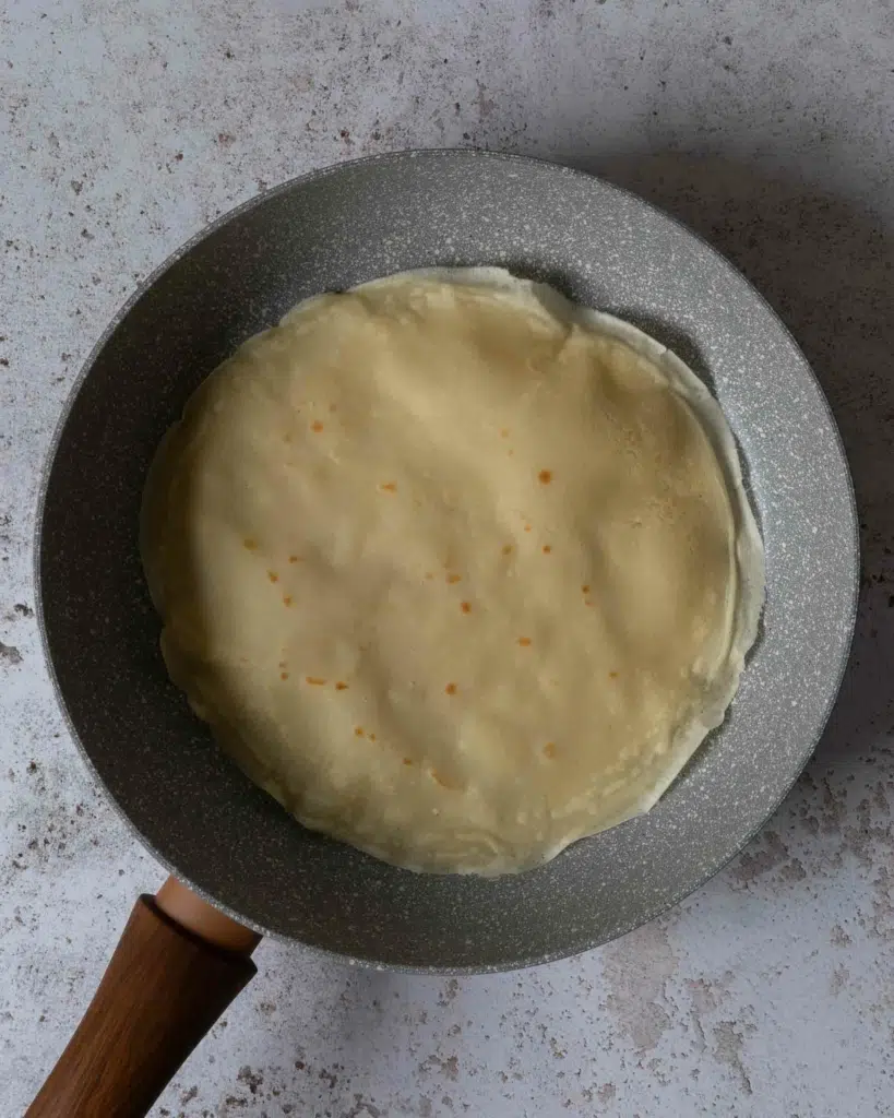 A frying pan with a freshly cooked crepe in it