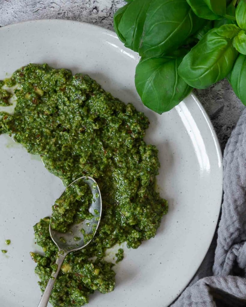 A close up photograph of nut free pesto spread onto a plate