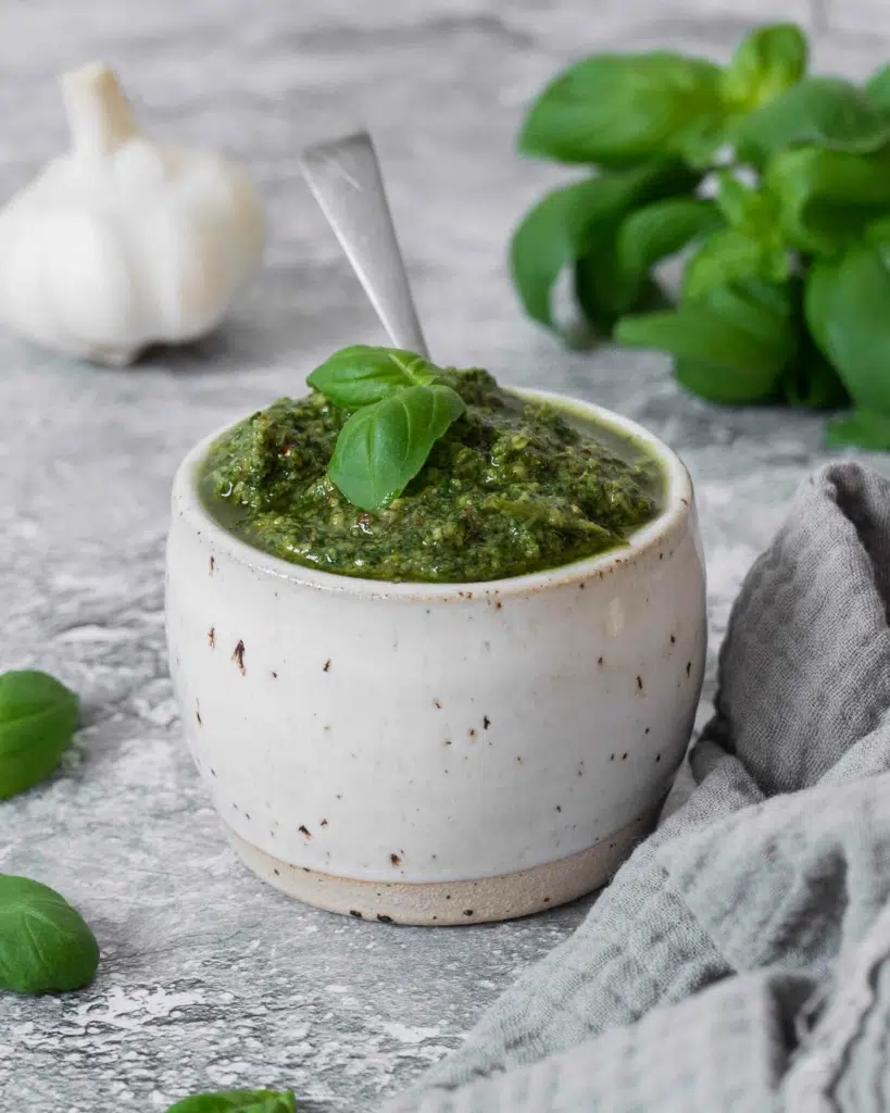 A dish of nut free pesto with a fresh green basil leaf sat on top