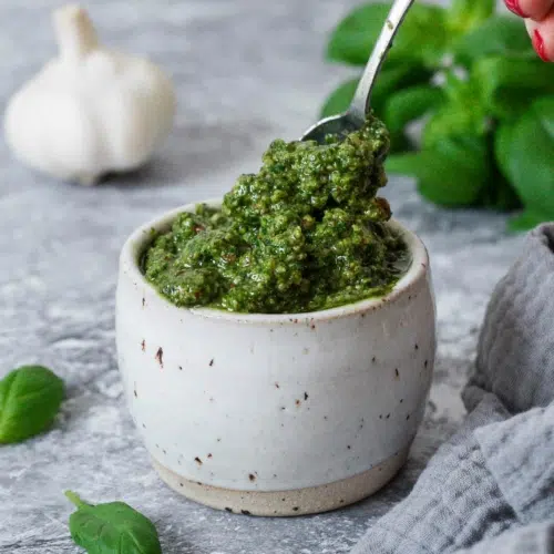 A dish of vibrant green nut free pesto, with a spoonful being taken out