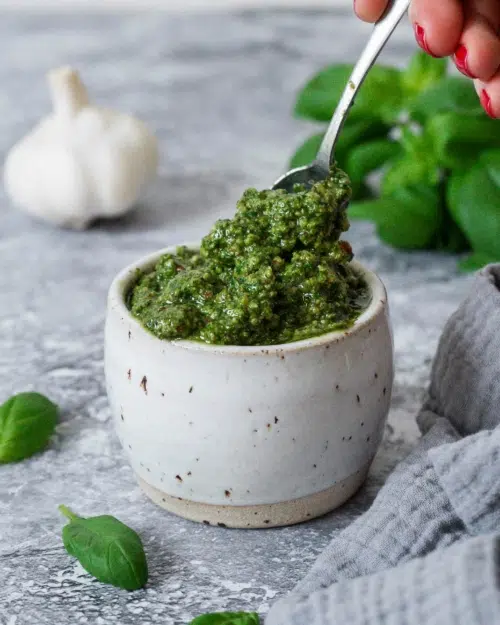 A dish of vibrant green nut free pesto, with a spoonful being taken out