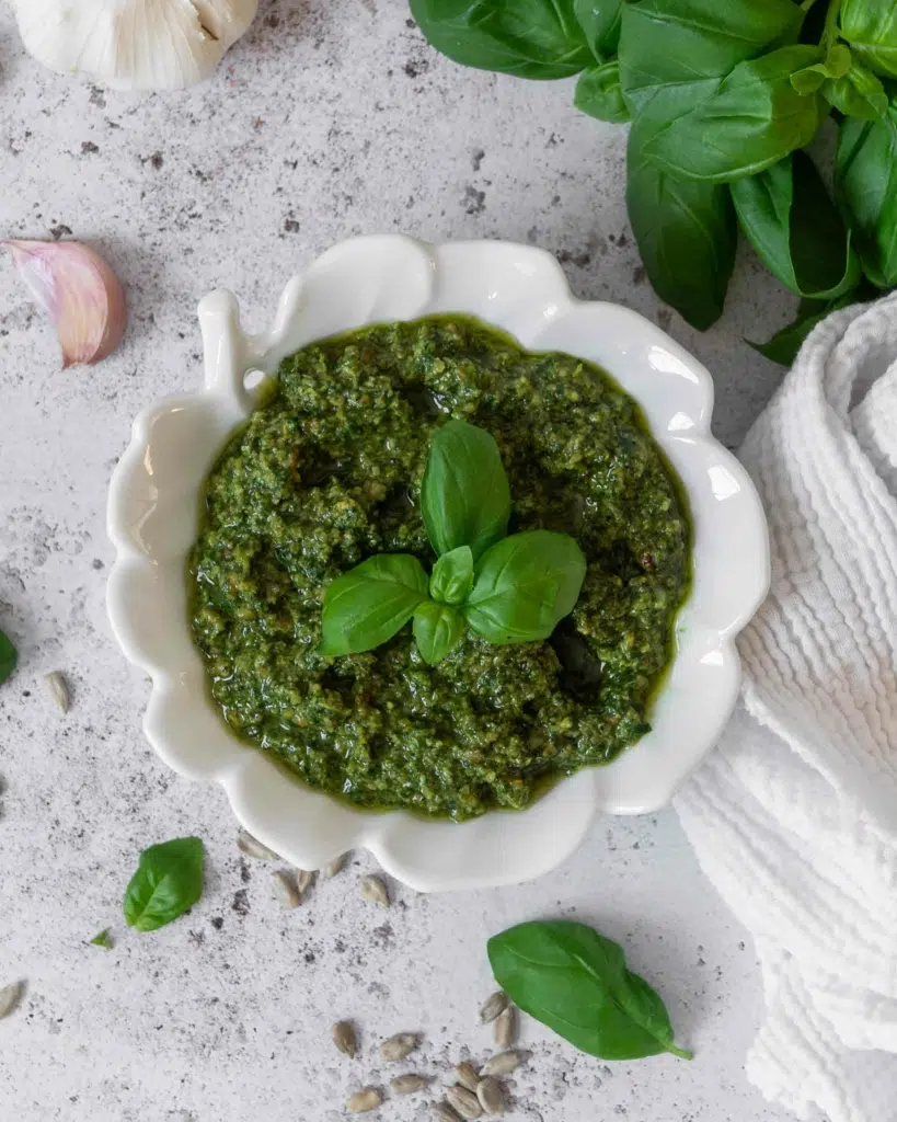 An overhead photograph of a bowl of vibrant green basil pesto without pine nuts.