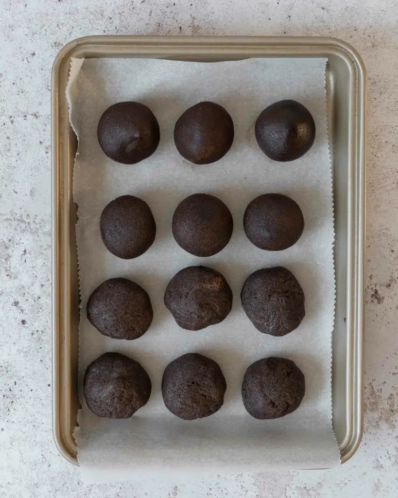 Chocolate peanut butter cake pops rolled out and placed on a lined tray