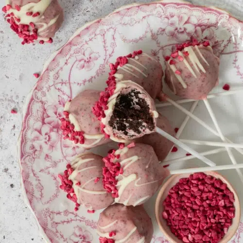 A plate of pretty pink white chocolate raspberry cake pops on a vintage floral pink plate.