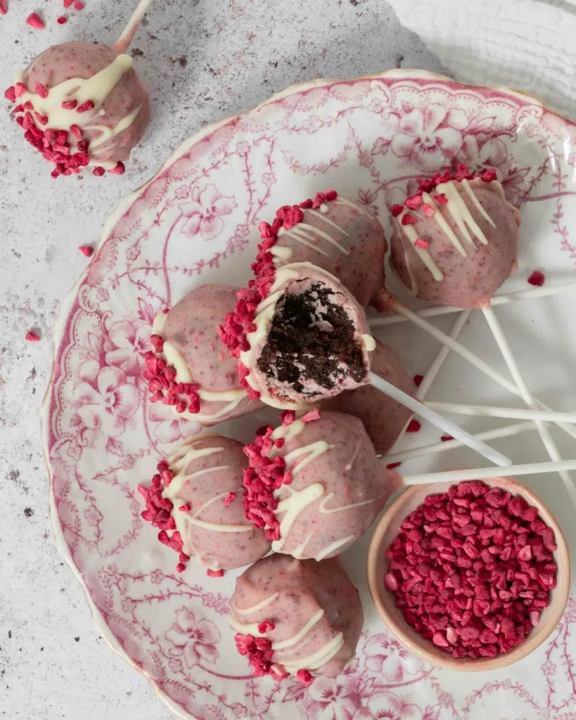 A plate of pretty pink white chocolate raspberry cake pops on a vintage floral pink plate.
