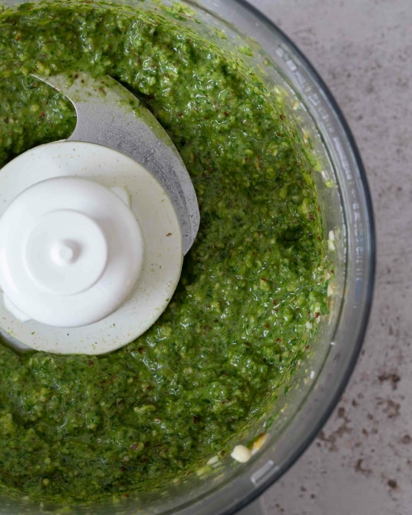 Freshly made vegan almond basil pesto in a food processor