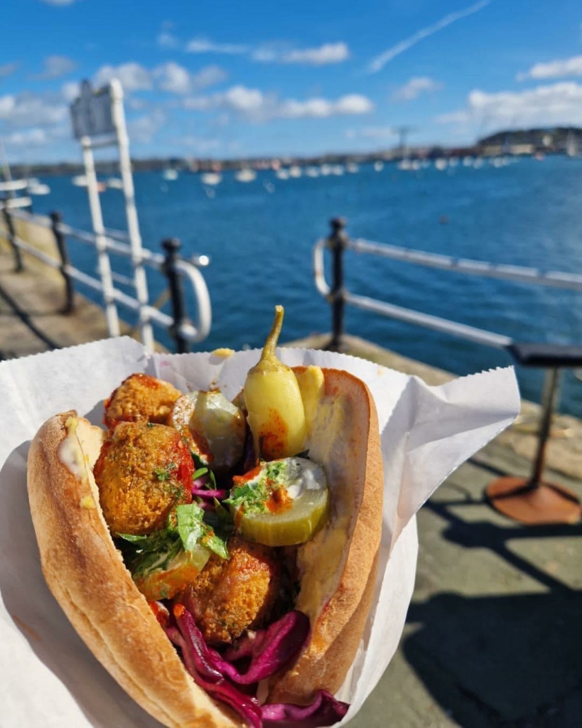 A pitta bread loaded with falafel next to the seaside