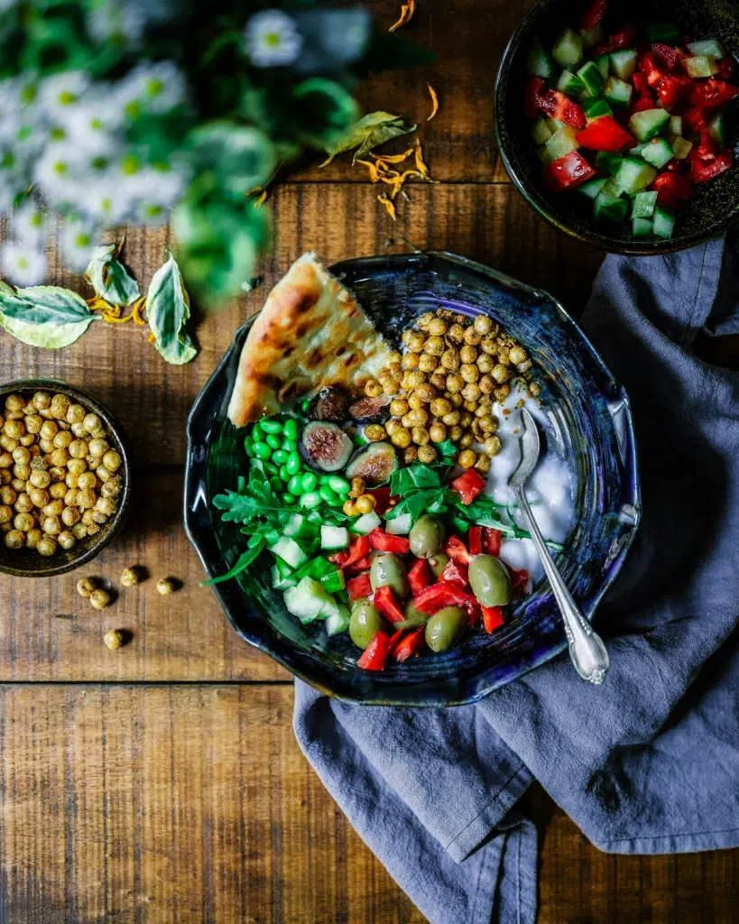 A colourful bowl of vegan food with fresh vegetables, chickpeas and bread