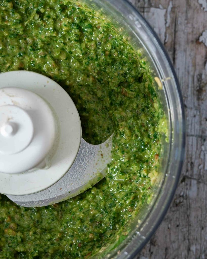A freshly made batch of vegan basil walnut pesto in a food processor