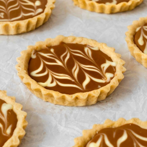 Vegan Biscoff tarts with white chocolate marbling laid out on a table