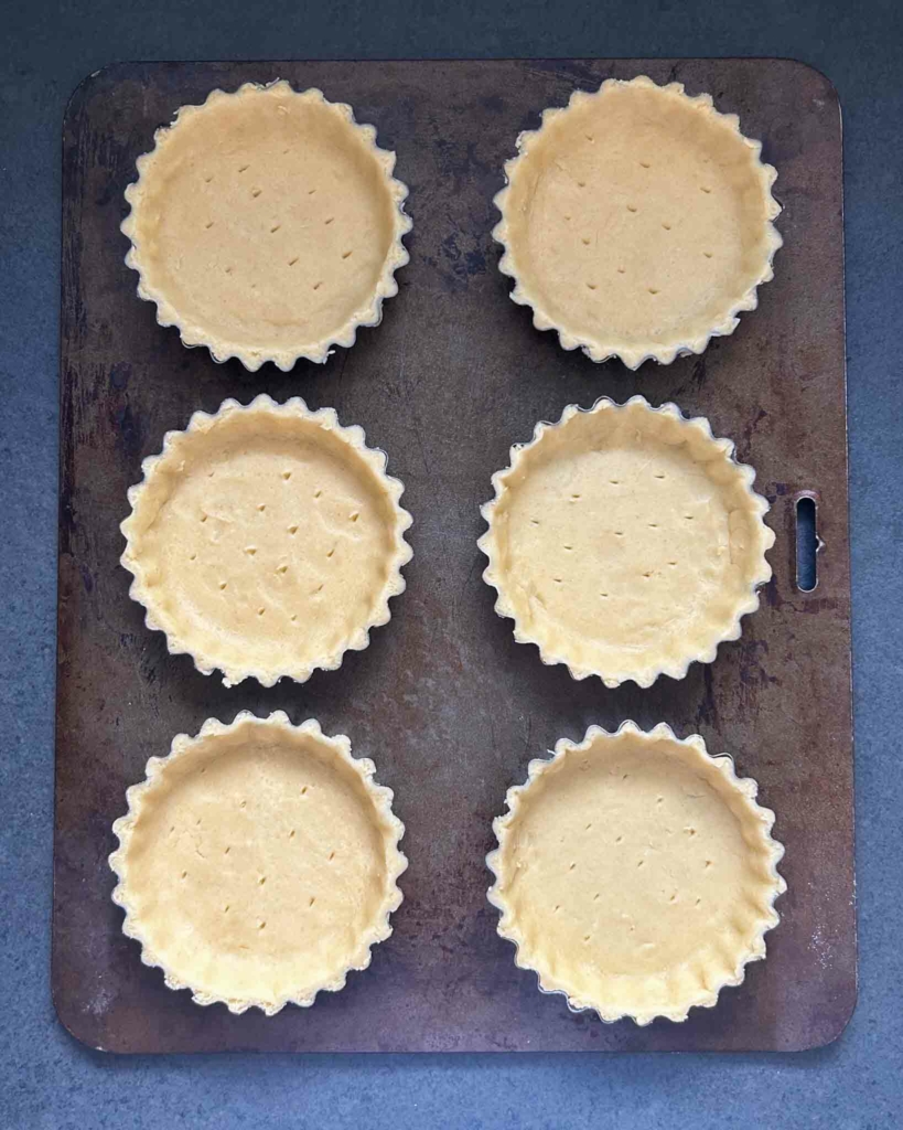 Unbaked vegan tart shells on a baking tray ready to be put in the oven
