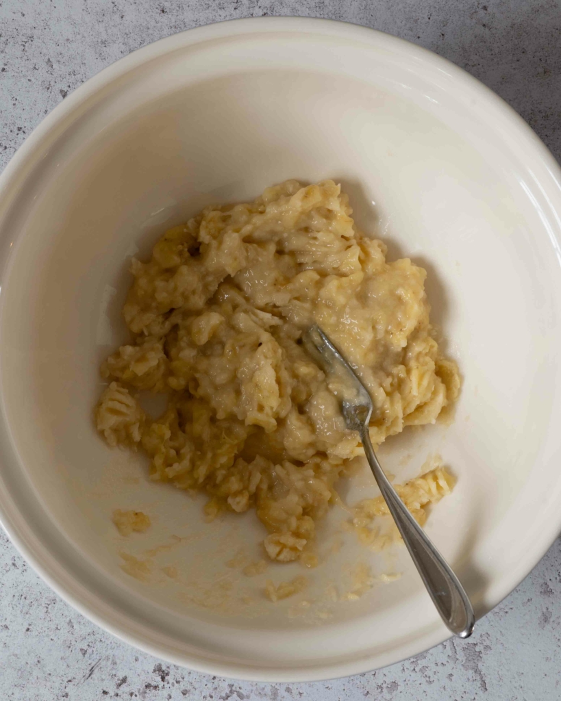 Mashed banana in a large mixing bowl