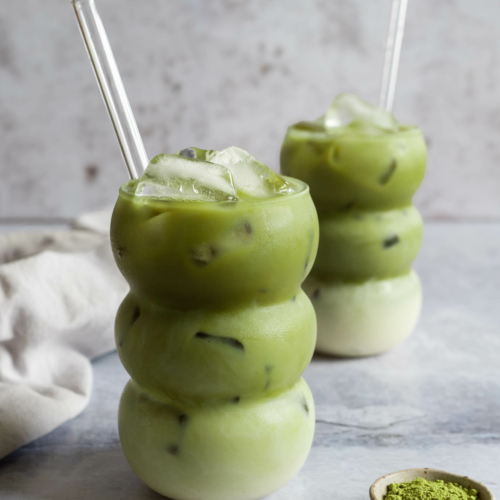 Two bubble shaped glasses filled with iced matcha latte