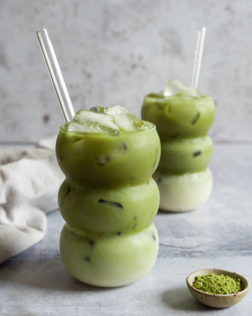 Two bubble shaped glasses filled with iced matcha latte