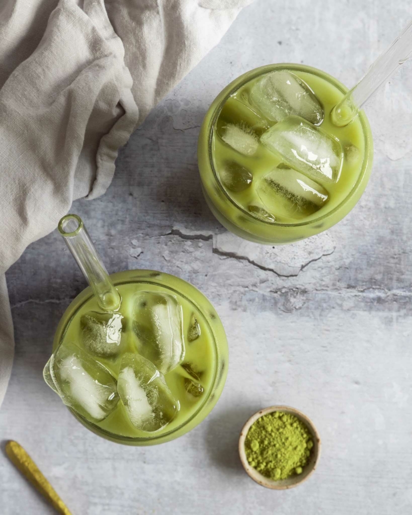 An overhead photograph of two glasses of iced vanilla matcha latte