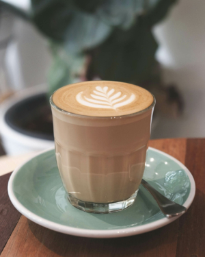 A small glass of milky oat milk coffee with latte art on top