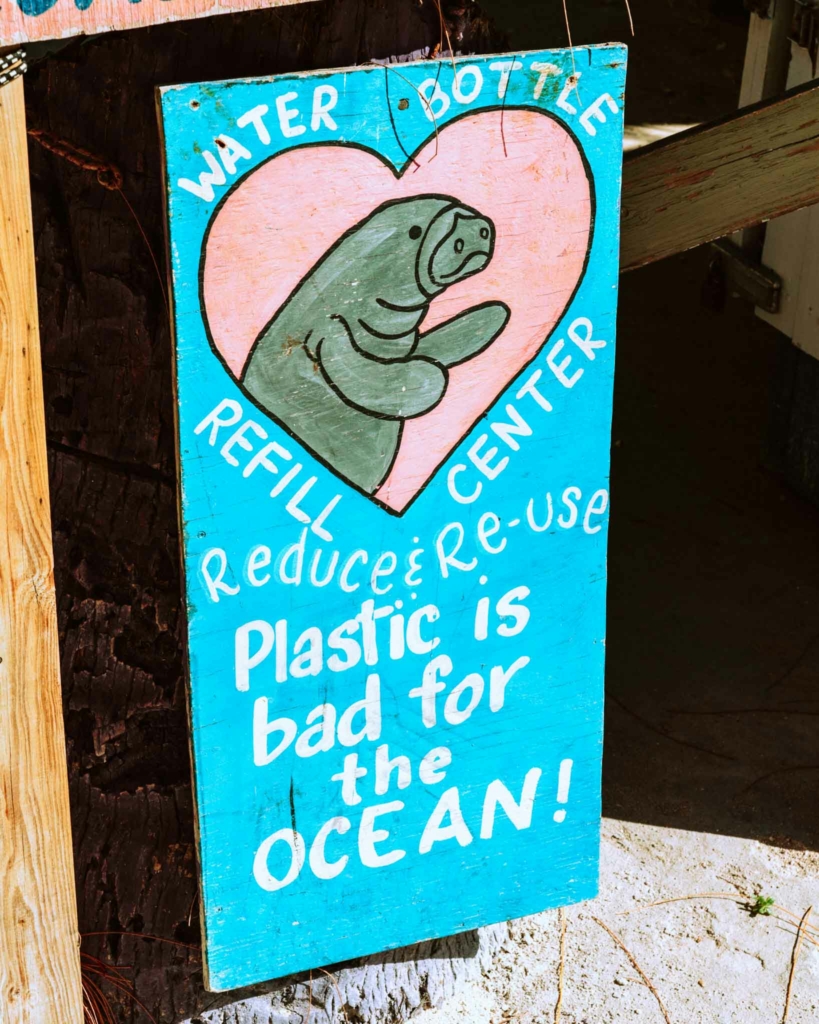 A blue sign with the slogan 'plastic is bad for the ocean! Reduce and reuse'