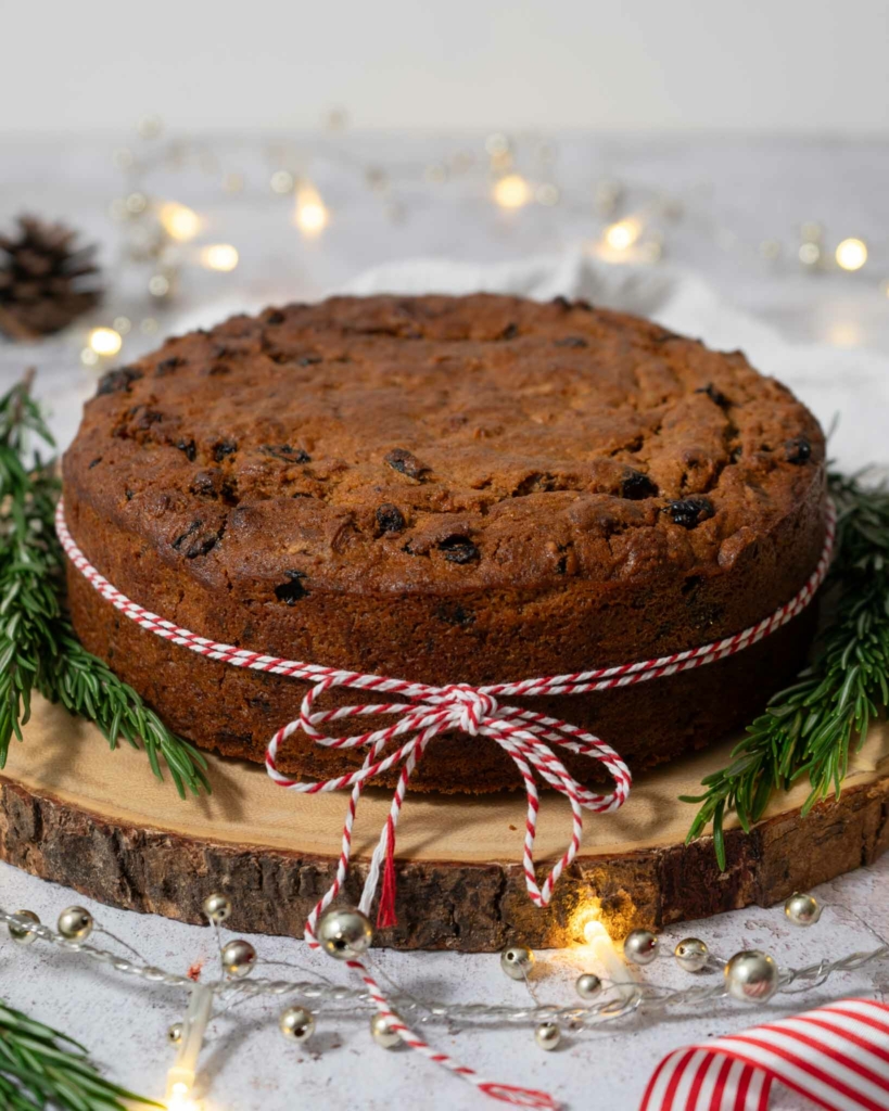 An unfrosted Christmas carrot cake tied with a red and white Christmas string