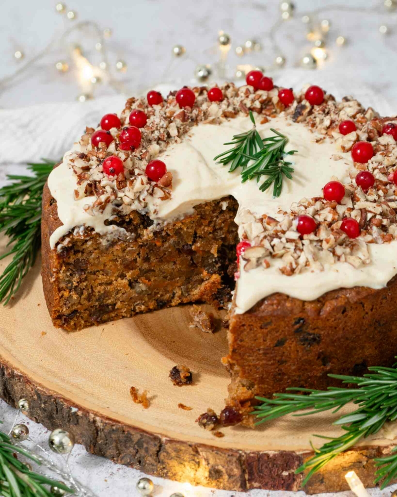 A Christmas carrot cake topped with festive icing, cranberries and chopped nuts