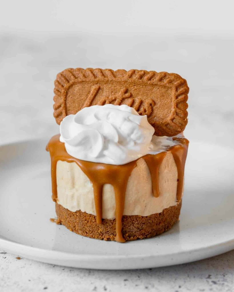 A vegan Biscoff mini cheesecake with dairy free whipped cream and a Biscoff biscuit on top