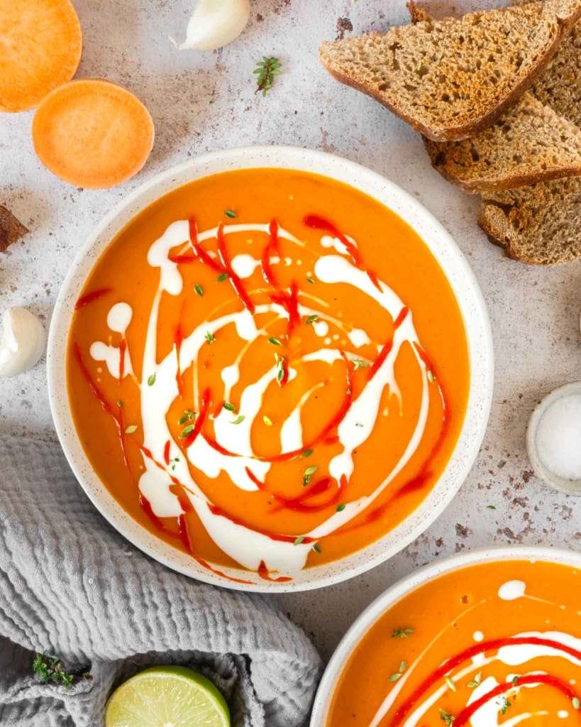 Two bowls of sweet potato chilli coconut soup on a tabletop