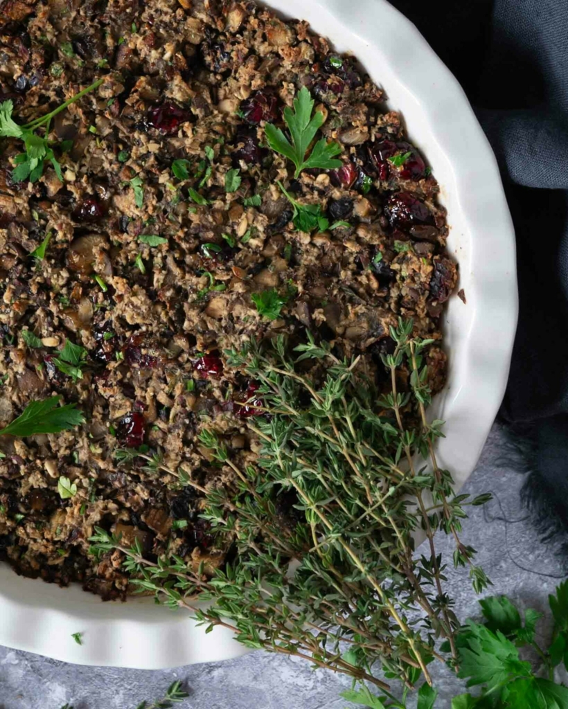 A close up photo of a dish of vegan chestnut, cranberry and mushroom stuffing