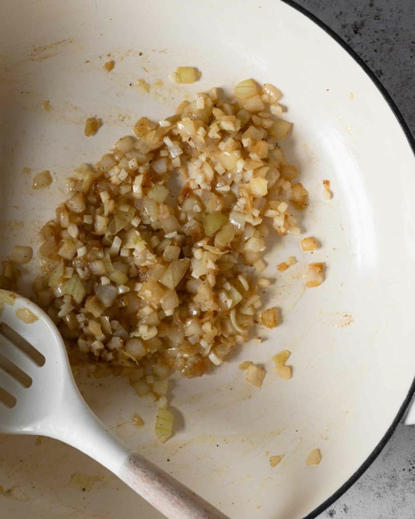 Diced onion being fried in a pan