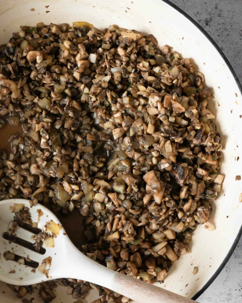 Diced mushrooms being fried in a pan