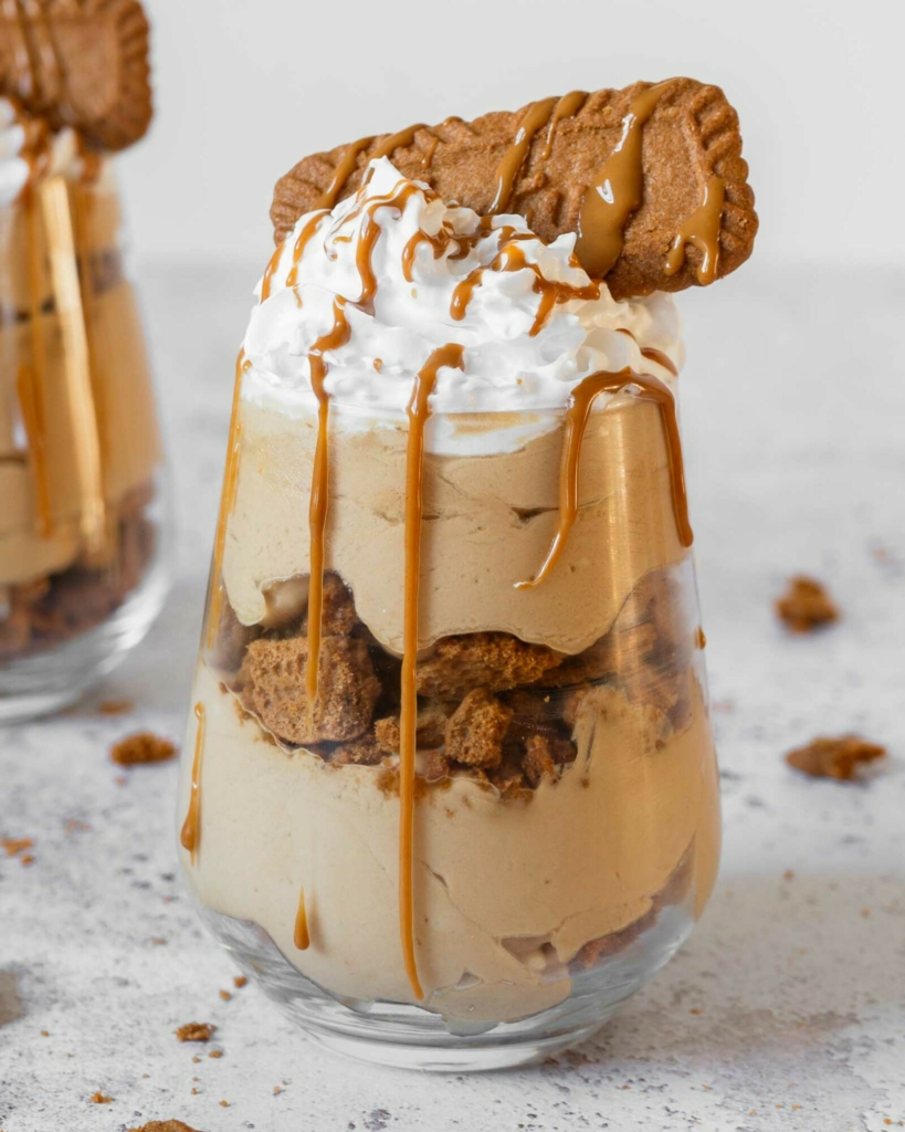 A layered no bake Biscoff cheesecake cup with a creamy cheesecake filling, layers of Biscoff biscuits and whipped vegan cream on top