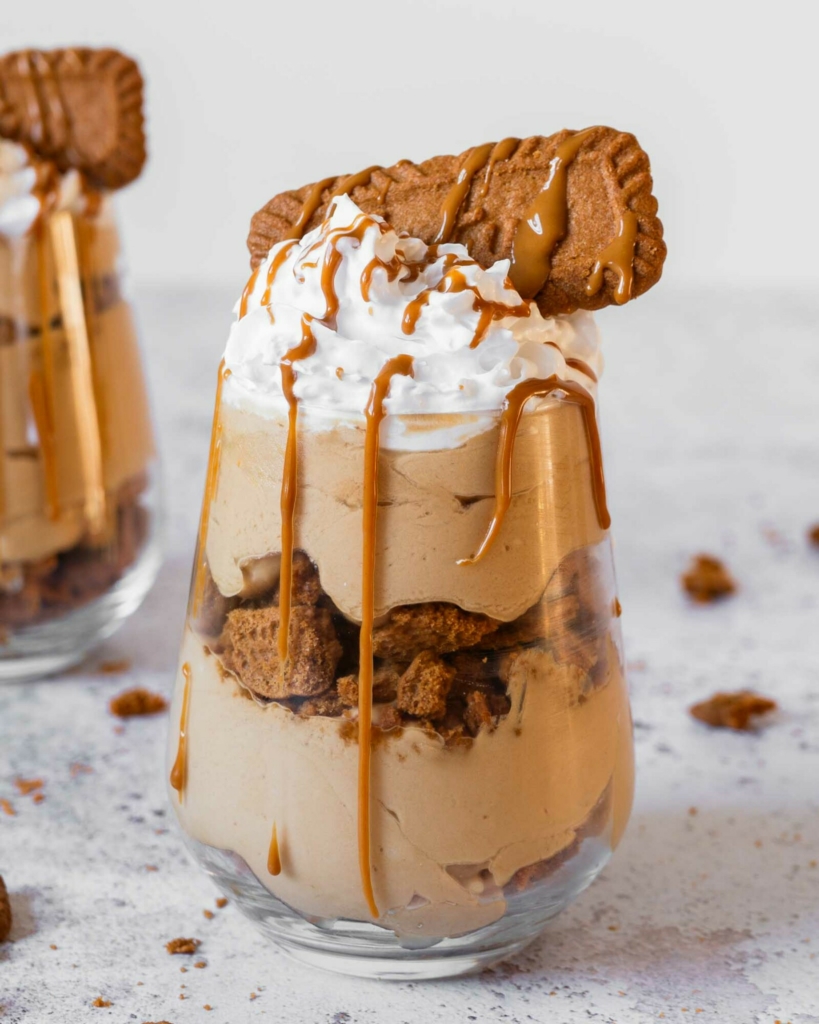 A layered no bake Biscoff cheesecake cup with a creamy cheesecake filling, layers of Biscoff biscuits and whipped vegan cream on top