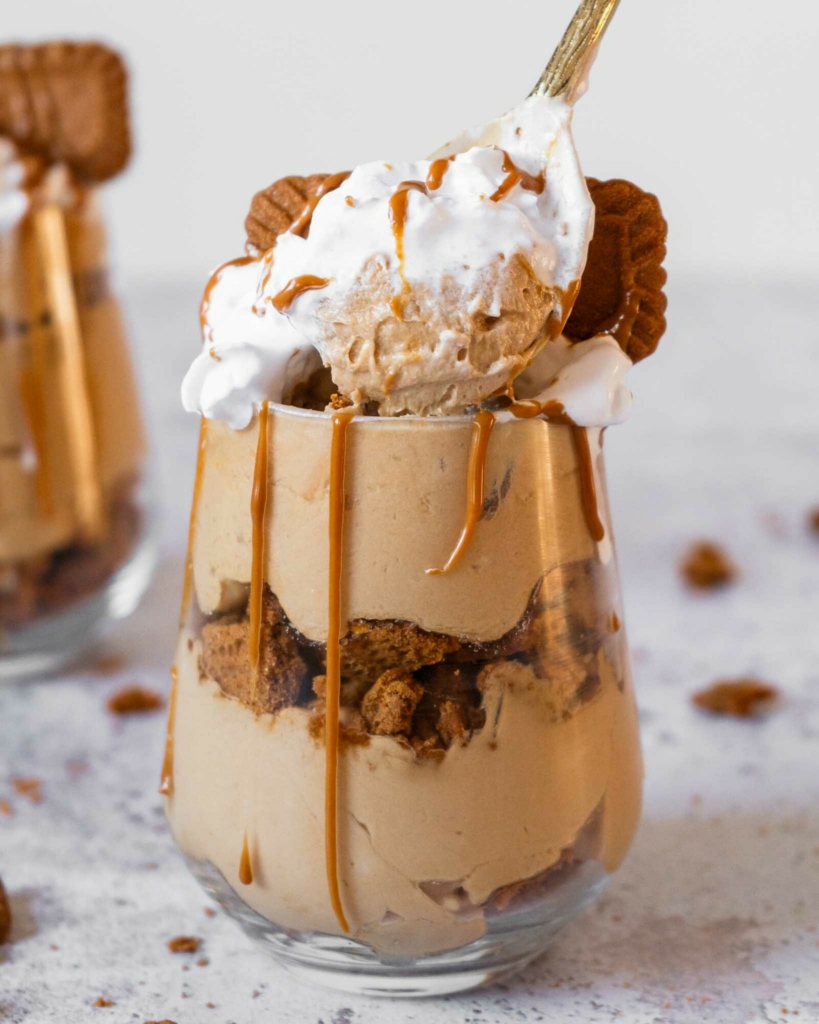 A layered no bake Biscoff cheesecake cup with a creamy cheesecake filling, layers of Biscoff biscuits and whipped vegan cream on top