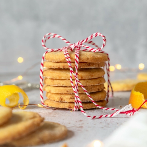 Vegan orange lemon shortbread cookies in a stack tied with a red and white Christmas string