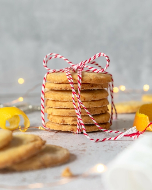 Vegan orange lemon shortbread cookies in a stack tied with a red and white Christmas string