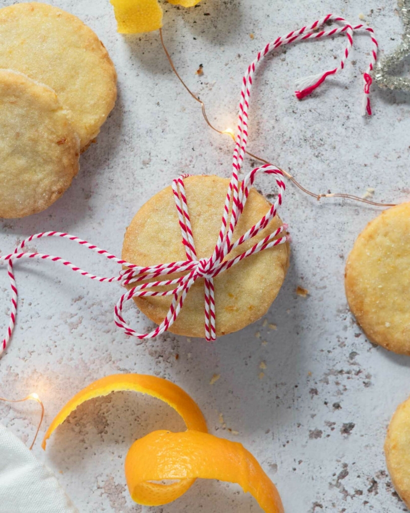 Vegan orange lemon shortbread cookies in a stack tied with a red and white Christmas string