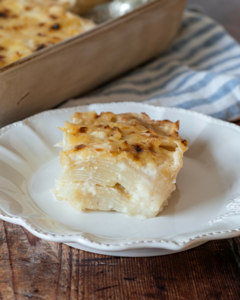 A neatly sliced portion of vegan potatoes dauphinoise sat on a pretty white plate