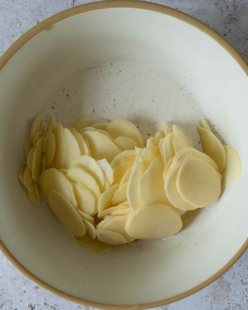 Cream and potato slices in a large mixing bowl