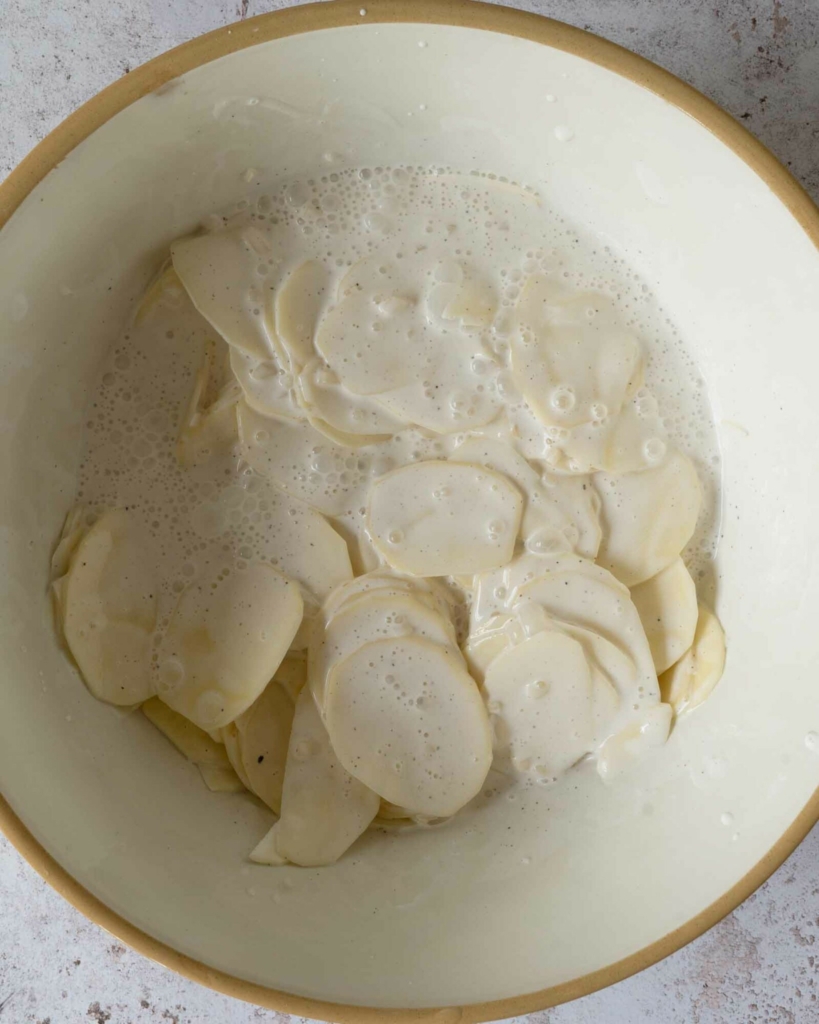Cream and potato slices in a large mixing bowl
